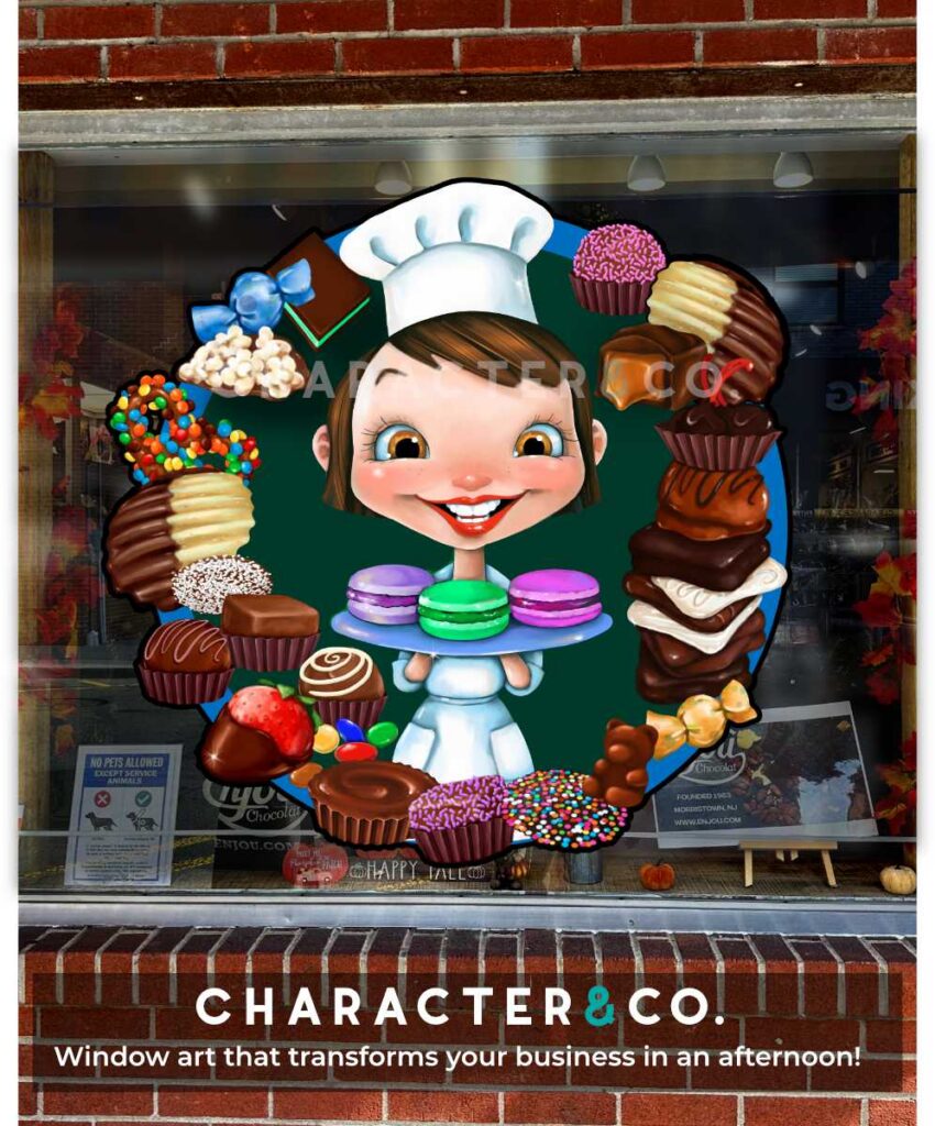 Custom painted vinyl storefront window graphic on a chocolate candy shop featuring a cartoon girl chef in a white hat holding colorful macarons, surrounded by chocolates, pretzels, strawberries, and candies in a circular design.